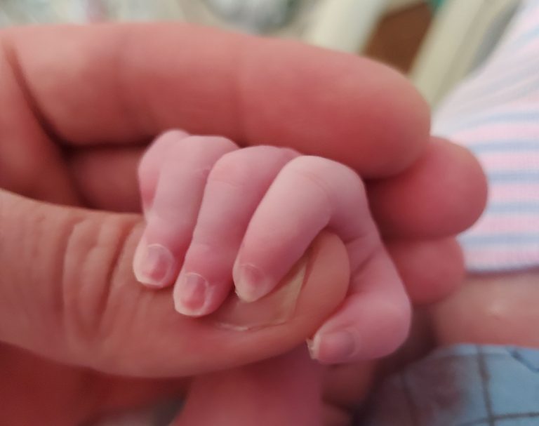 Baby holding her dad's finger