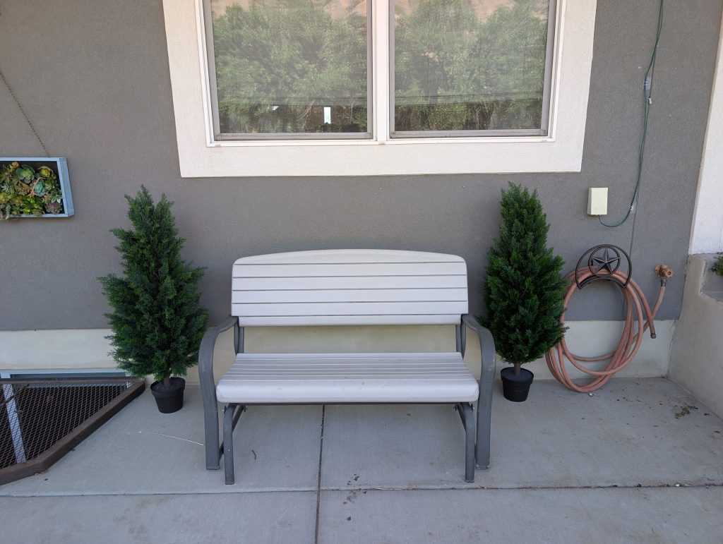 Artificial pine trees by our rocking bench